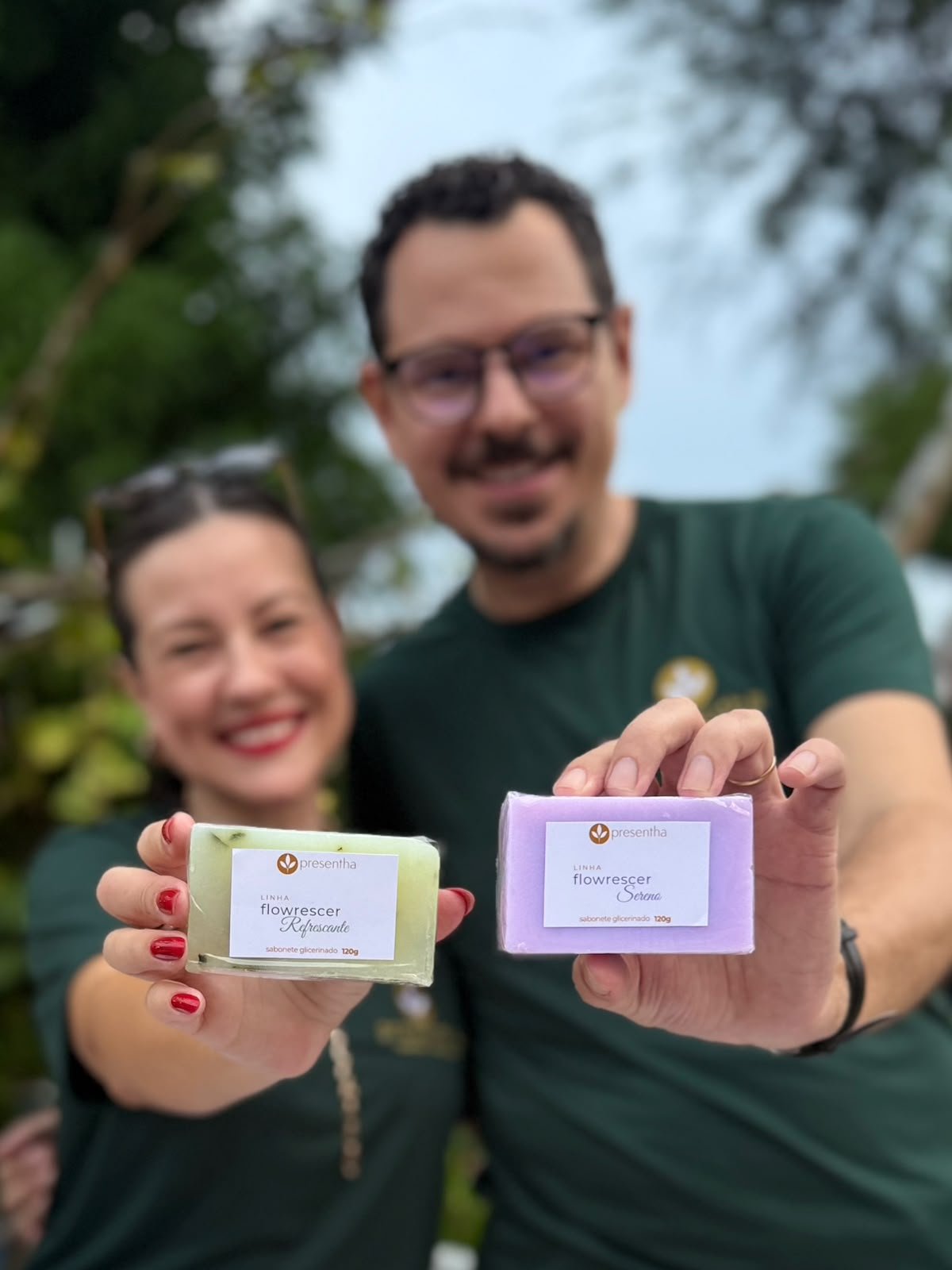 Tiago e Esther segurando sabonetes artesanais da Presentha, com mãos e produtos em destaque